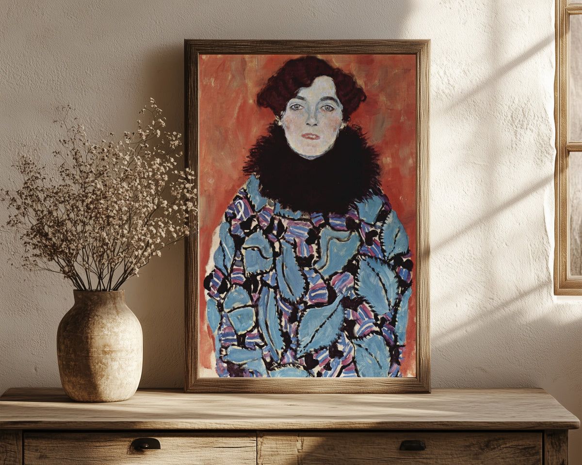 Framed art print of Portrait of Johanna Staude by Gustav Klimt, in a dark wood frame leaning on a rustic console beside dried flowers