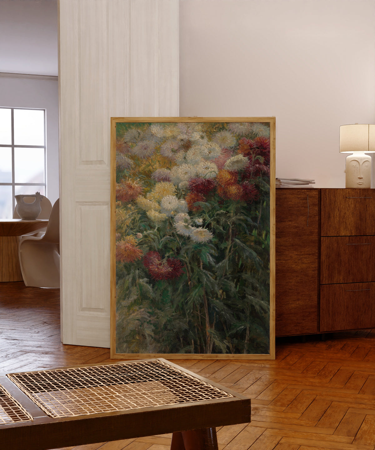Framed art print of Chrysanthemums in the Garden at… by Gustave Caillebotte, in a light wood frame leaning in a warm room with a parquet floor