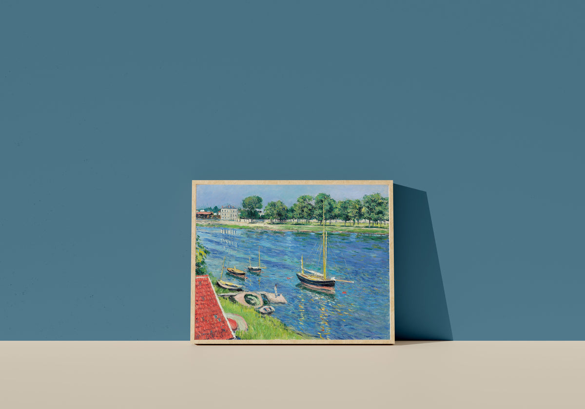 Framed art print of La Seine à Argenteuil, bateaux au mouillage by Gustave Caillebotte, in a light wood frame leaning on a blue wall