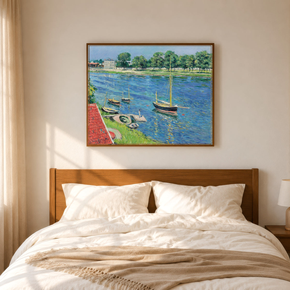 Framed art print of La Seine à Argenteuil, bateaux au mouillage by Gustave Caillebotte, in a slim wood frame above a bed in a sunlit bedroom