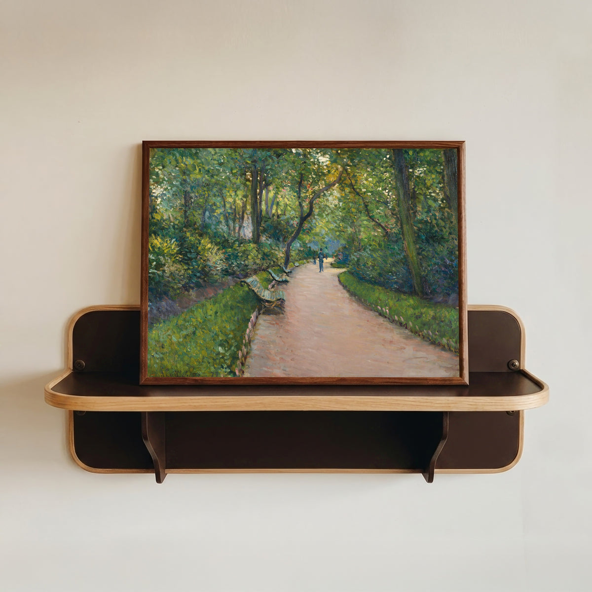 Framed art print of Le Parc Monceau by Gustave Caillebotte, in a dark wood frame resting on a wall shelf