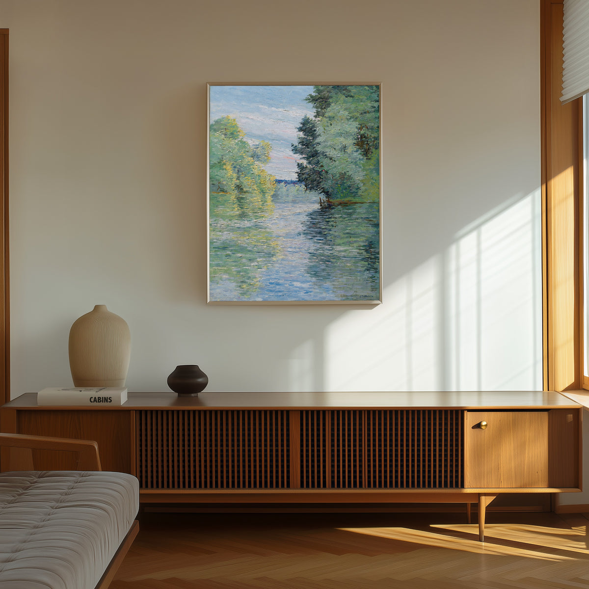 Framed art print of Le Petit bras de la Seine à Argenteuil by Gustave Caillebotte, in a thin light frame on a sunlit wall above a wooden sideboard
