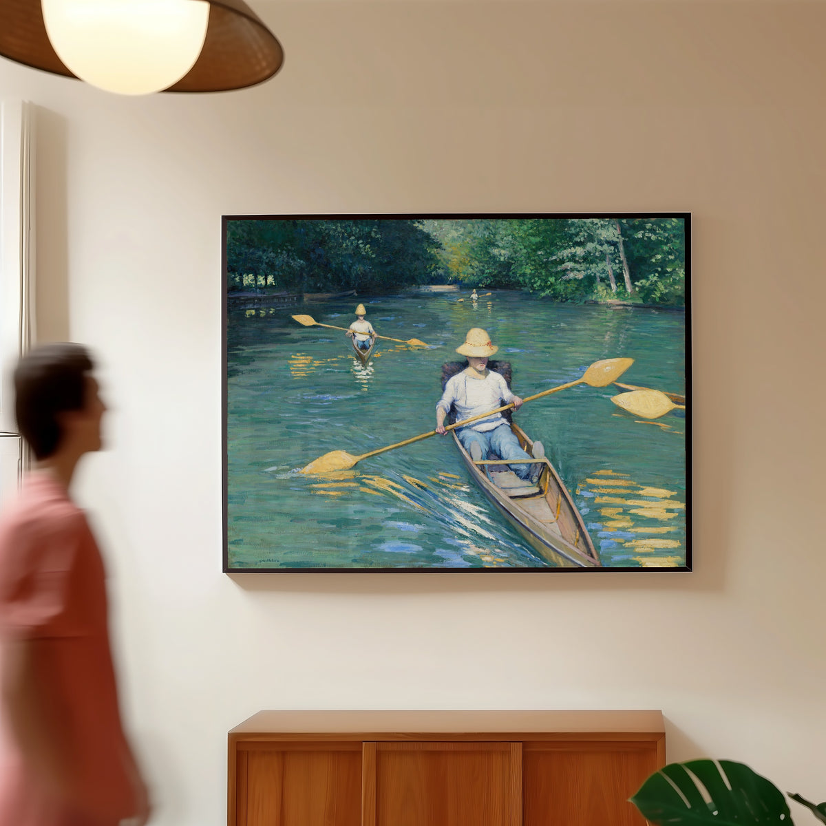 Framed art print of Skiffs by Gustave Caillebotte, in a slim black frame on a warm wall in a sunlit room