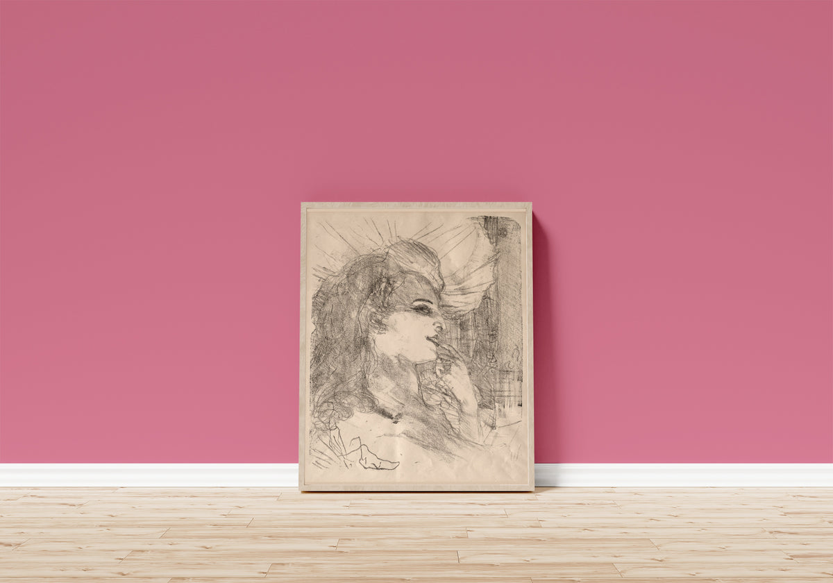 Framed art print of Anna Held by Henri de Toulouse-Lautrec, in a light wood frame leaning on a pink wall above a wooden floor