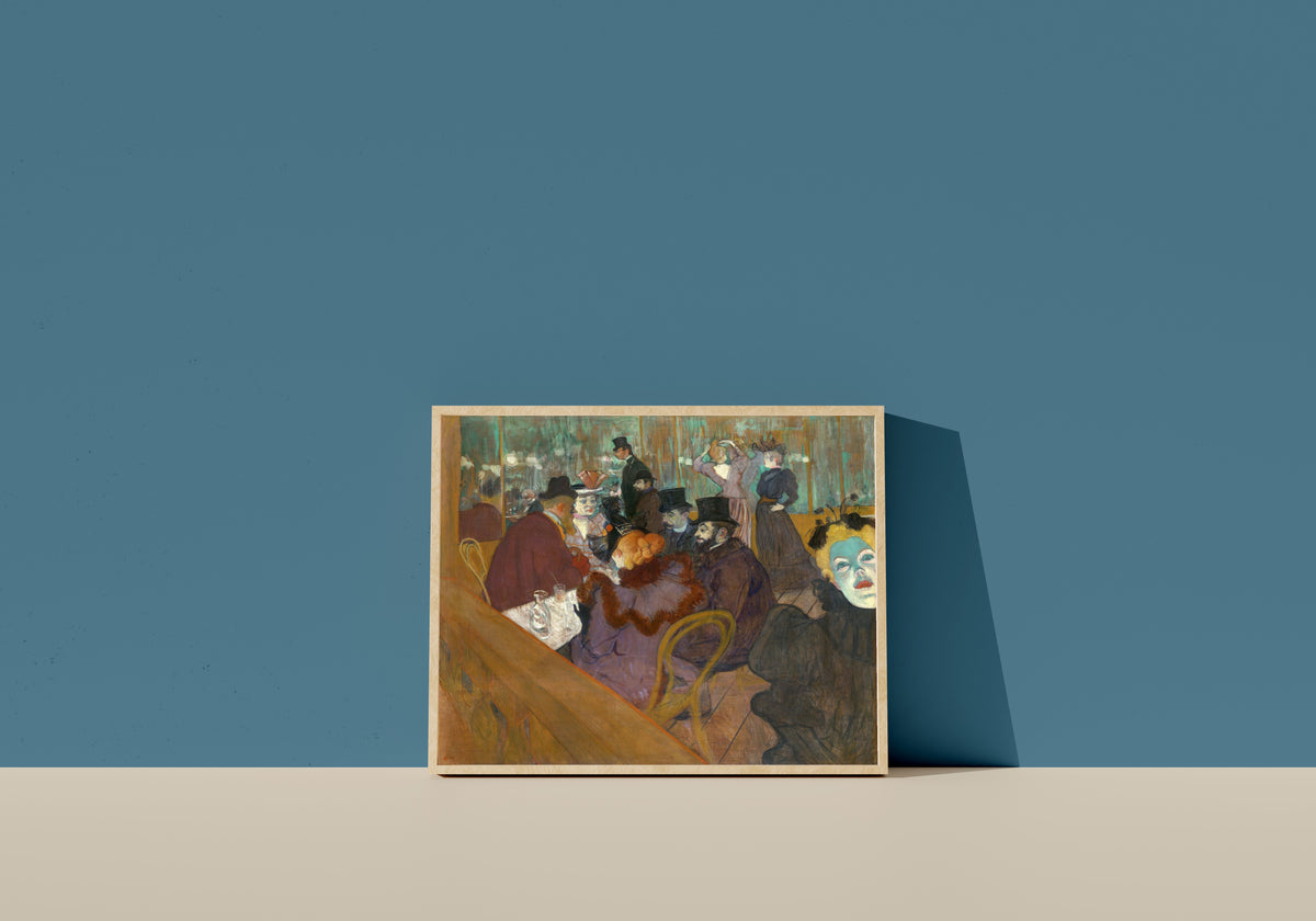 Framed art print of At the Moulin Rouge by Henri de Toulouse-Lautrec, in a light wood frame leaning on a blue wall