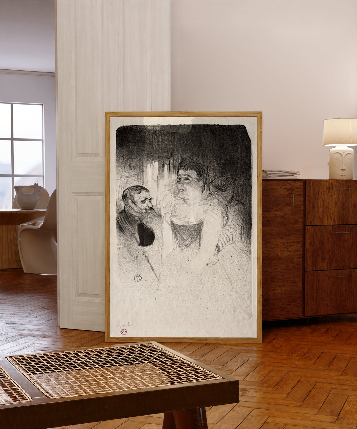 Framed art print of Judic in the Loge by Henri de Toulouse-Lautrec, in a light wood frame leaning in a warm room with a parquet floor