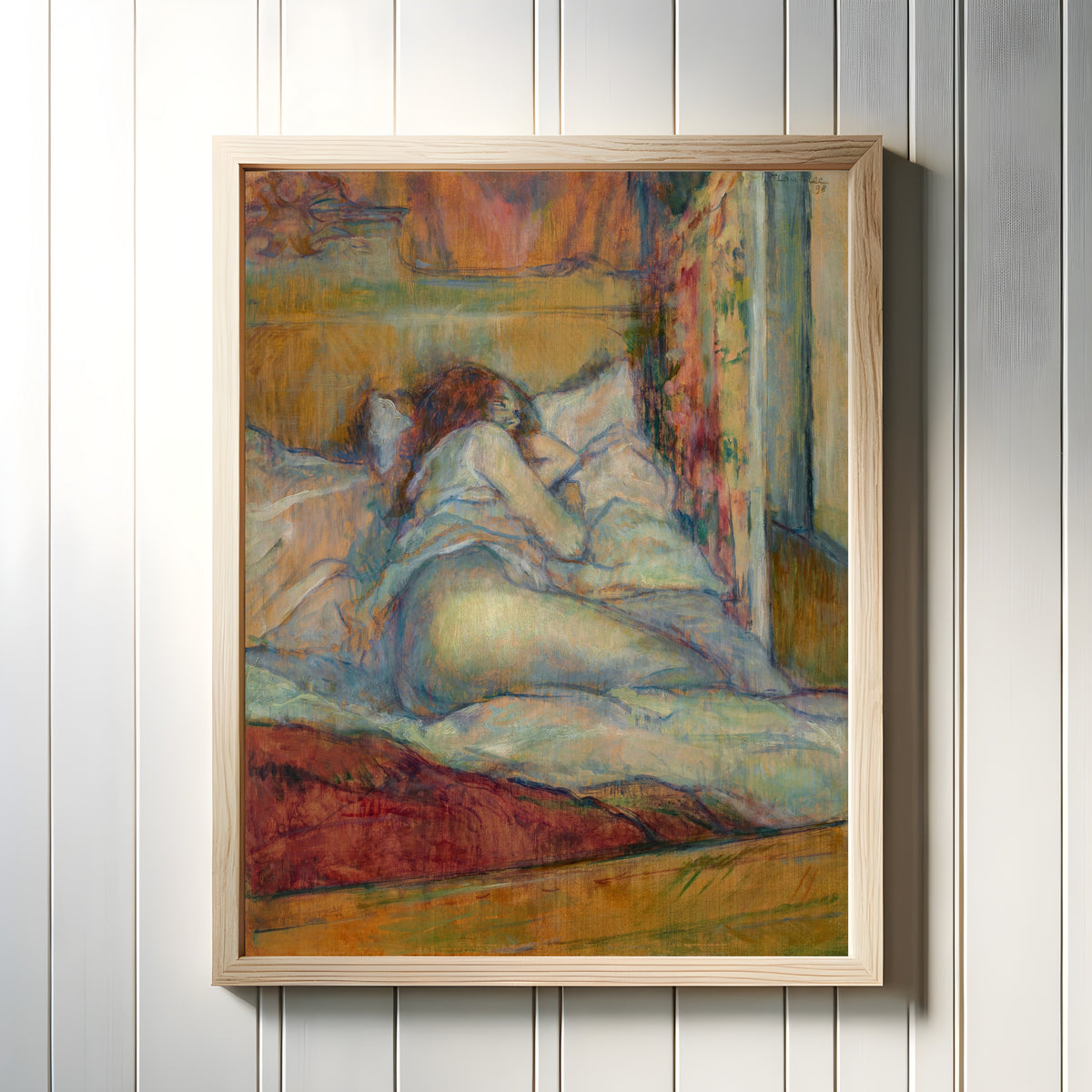 Framed art print of Le Lit (Woman Seen from Behind) by Henri de Toulouse-Lautrec, in a light wood frame on a white panelled wall