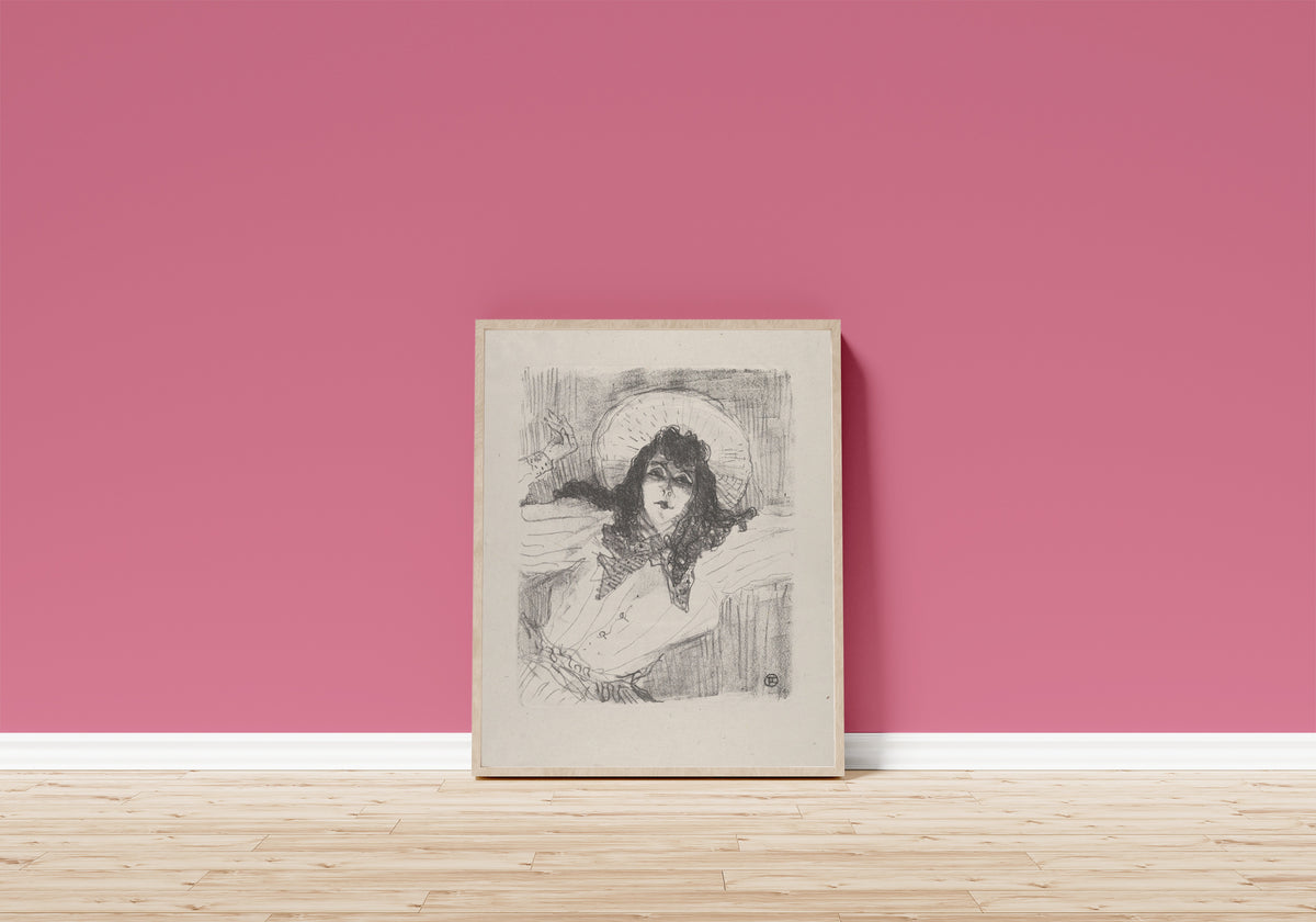 Framed art print of May Belfort (Bust Portrait) by Henri de Toulouse-Lautrec, in a light wood frame leaning on a pink wall above a wooden floor