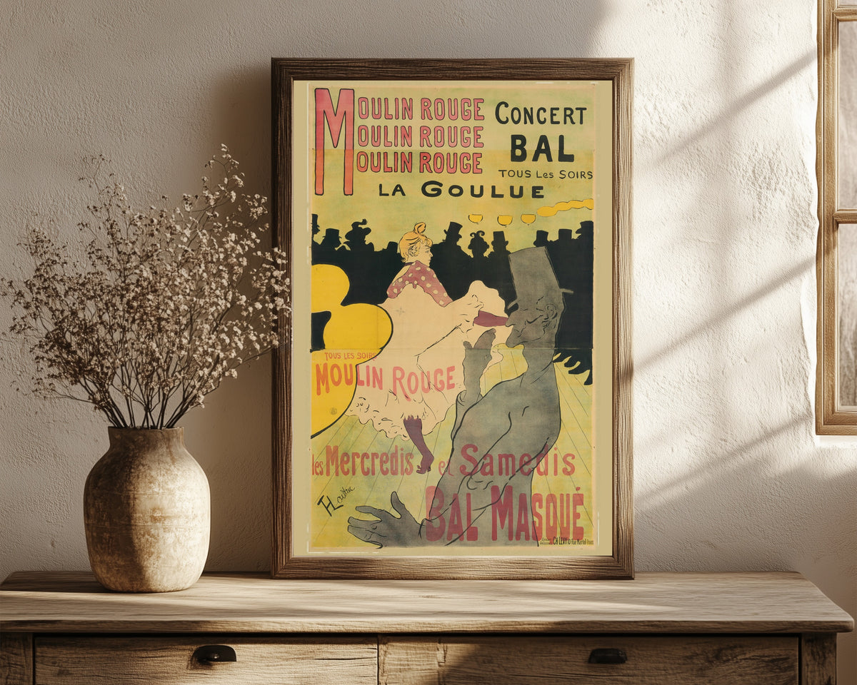 Framed art print of Moulin Rouge: La Goulue by Henri de Toulouse-Lautrec, in a dark wood frame leaning on a rustic console beside dried flowers