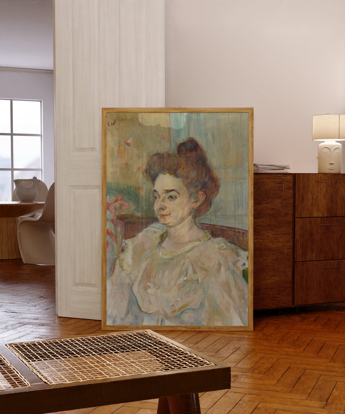 Framed art print of Portrait de Béatrice Tapié de Céleyran by Henri de Toulouse-Lautrec, in a light wood frame leaning in a warm room with a parquet floor