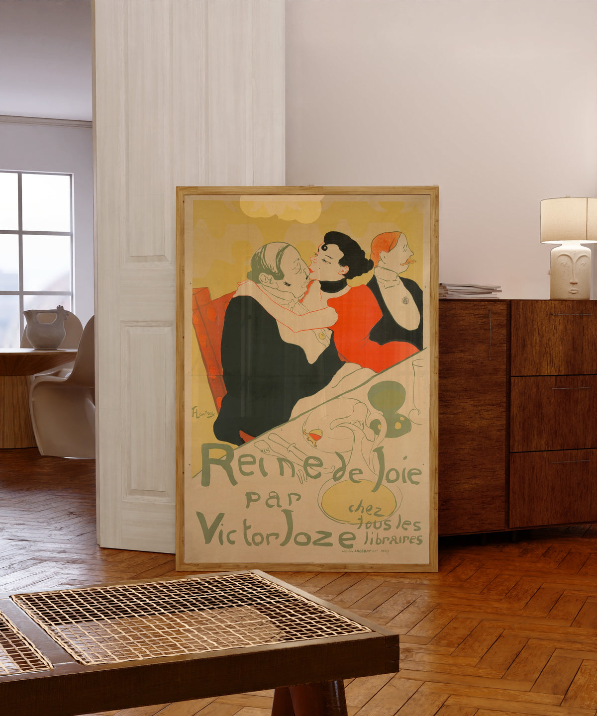 Framed art print of Reine de Joie by Henri de Toulouse-Lautrec, in a light wood frame leaning in a warm room with a parquet floor