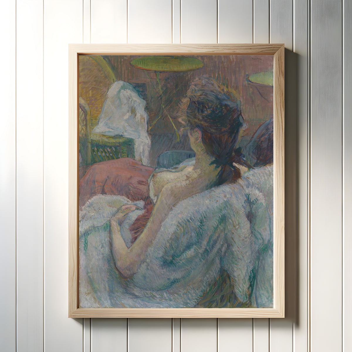 Framed art print of The Model Resting by Henri de Toulouse-Lautrec, in a light wood frame on a white panelled wall