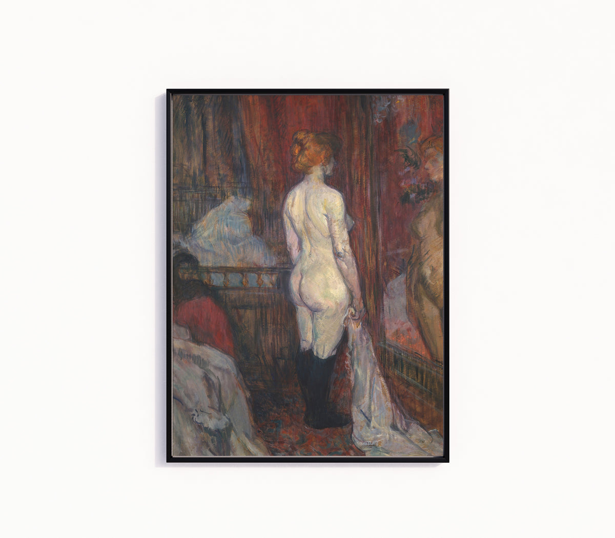 Framed art print of Woman before a Mirror by Henri de Toulouse-Lautrec, in a slim black frame on a plain white wall