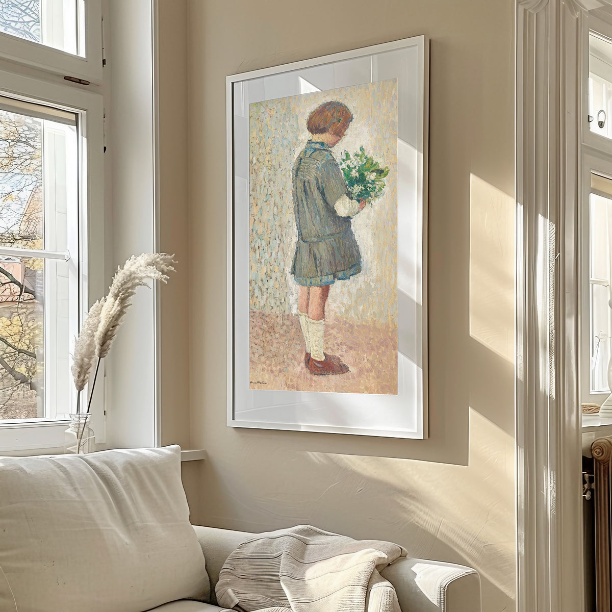 Framed art print of Fillette en tablier d’écolière tenant un bouquet by Henri Martin, in a sunlit living room above a sofa