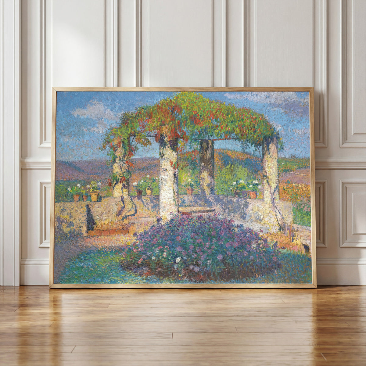 Framed art print of La Tonnelle de l'angle nord-ouest du parc de Marquayrol by Henri Martin, in a light wood frame leaning against a panelled white wall