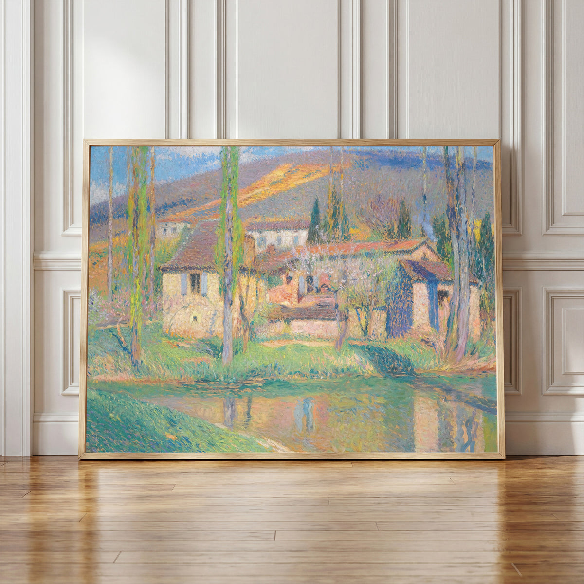 Framed art print of Labastide-du-Vert (Houses Reflected in the River) by Henri Martin, in a light wood frame leaning against a panelled white wall