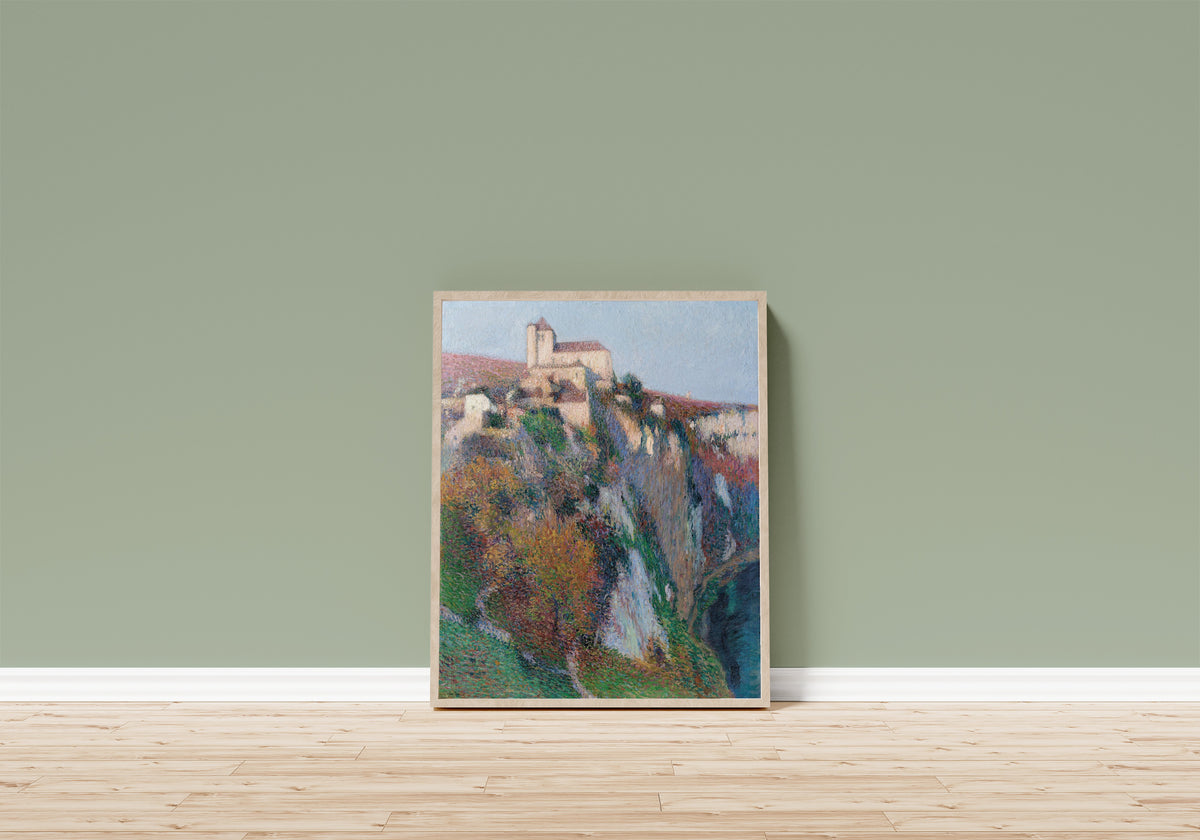 Framed art print of L'église Saint-Cirq Lapopie perchée sur la… by Henri Martin, in a light wood frame leaning on a sage green wall above a wooden floor