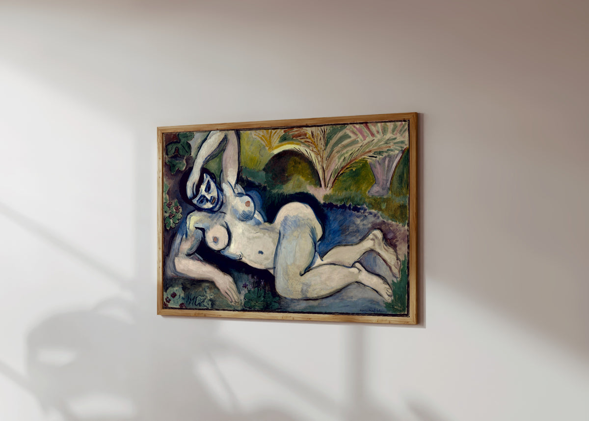 Framed art print of Blue Nude (Souvenir de Biskra) by Henri Matisse, in a light wood frame on a sunlit white wall, seen at a slight angle