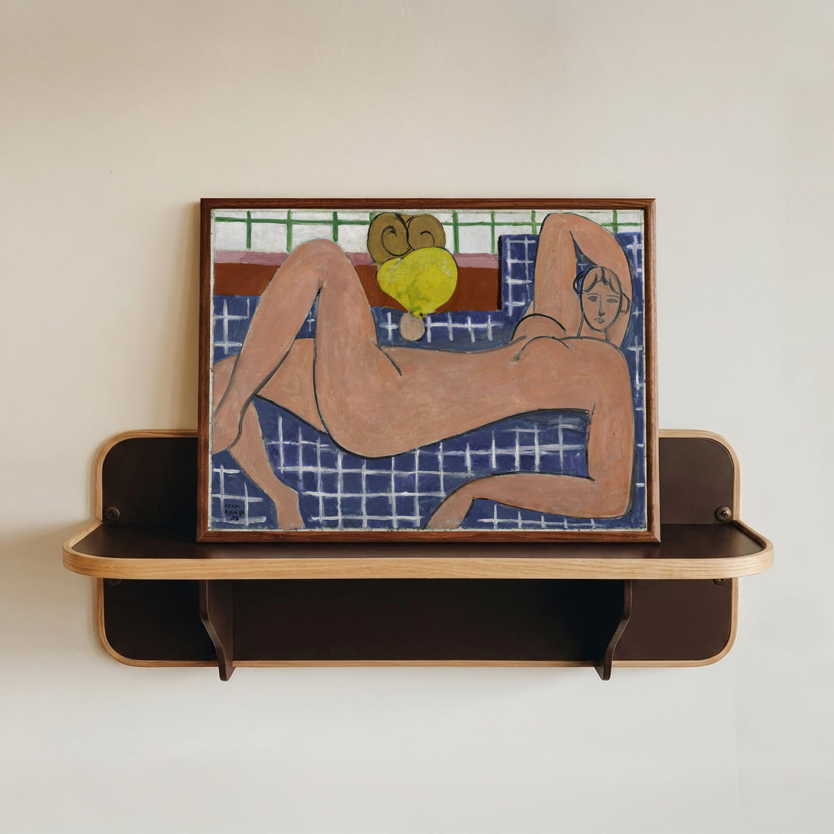 Framed art print of Large Reclining Nude (The Pink Nude) by Henri Matisse, in a dark wood frame resting on a wall shelf