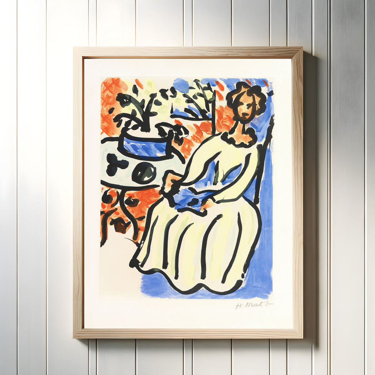 Framed art print of Marie-José in a Yellow Dress by Henri Matisse, in a light wood frame on a white panelled wall