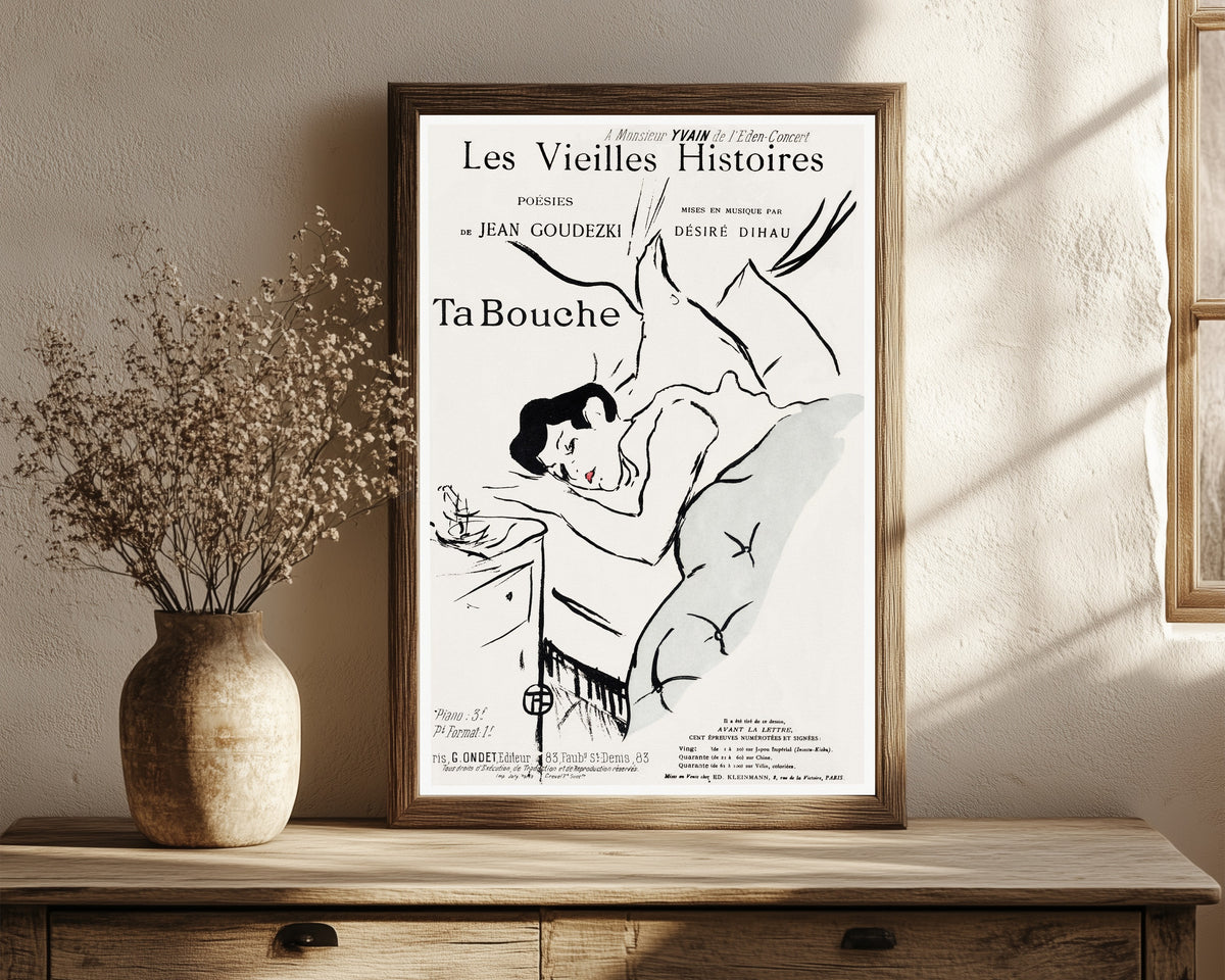 Framed art print of Ta Bouche by Henri de Toulouse-Lautrec, in a dark wood frame leaning on a rustic console beside dried flowers