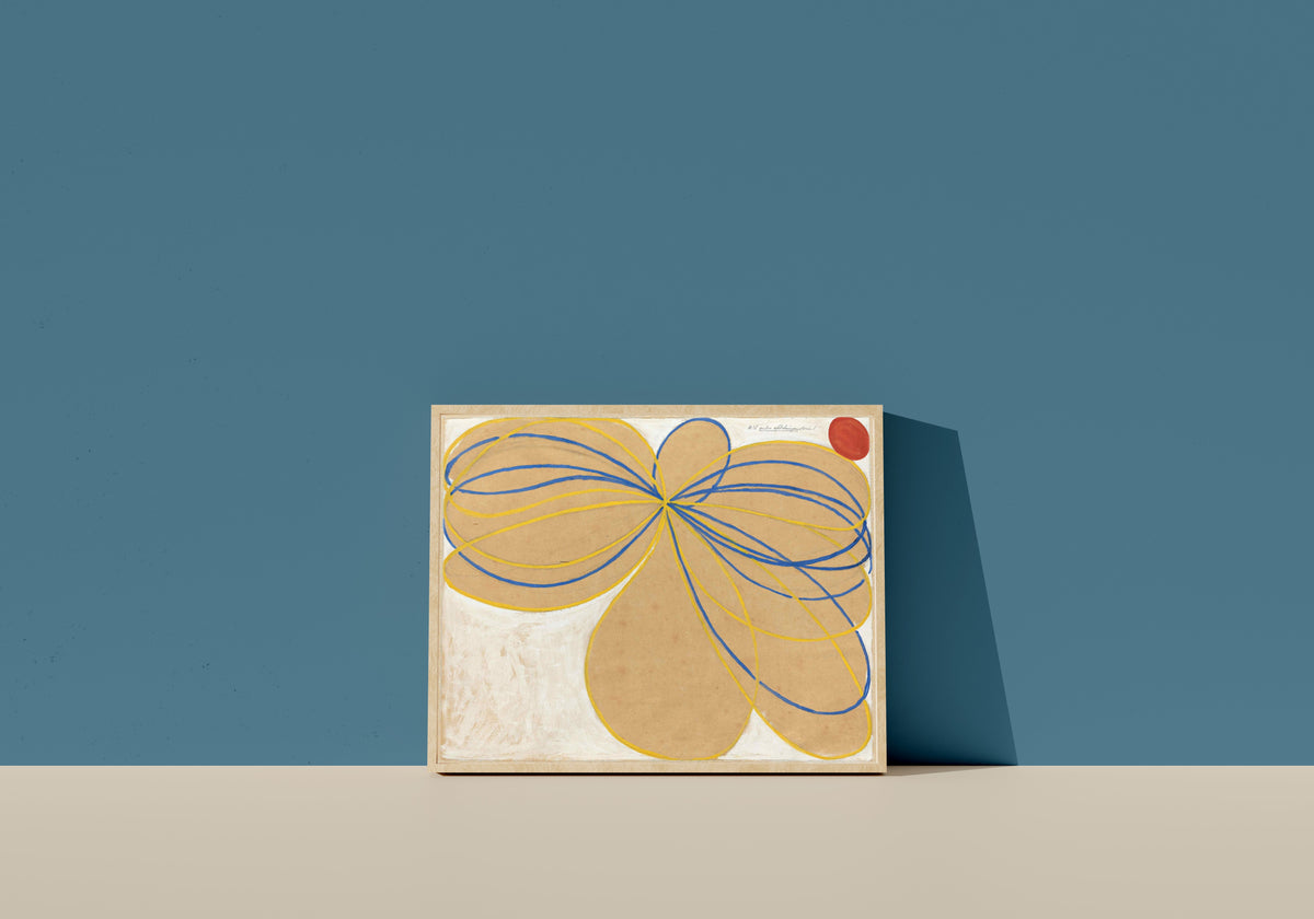 Framed art print of The Seven-Pointed Star No. 1 by Hilma af Klint, in a light wood frame leaning on a blue wall