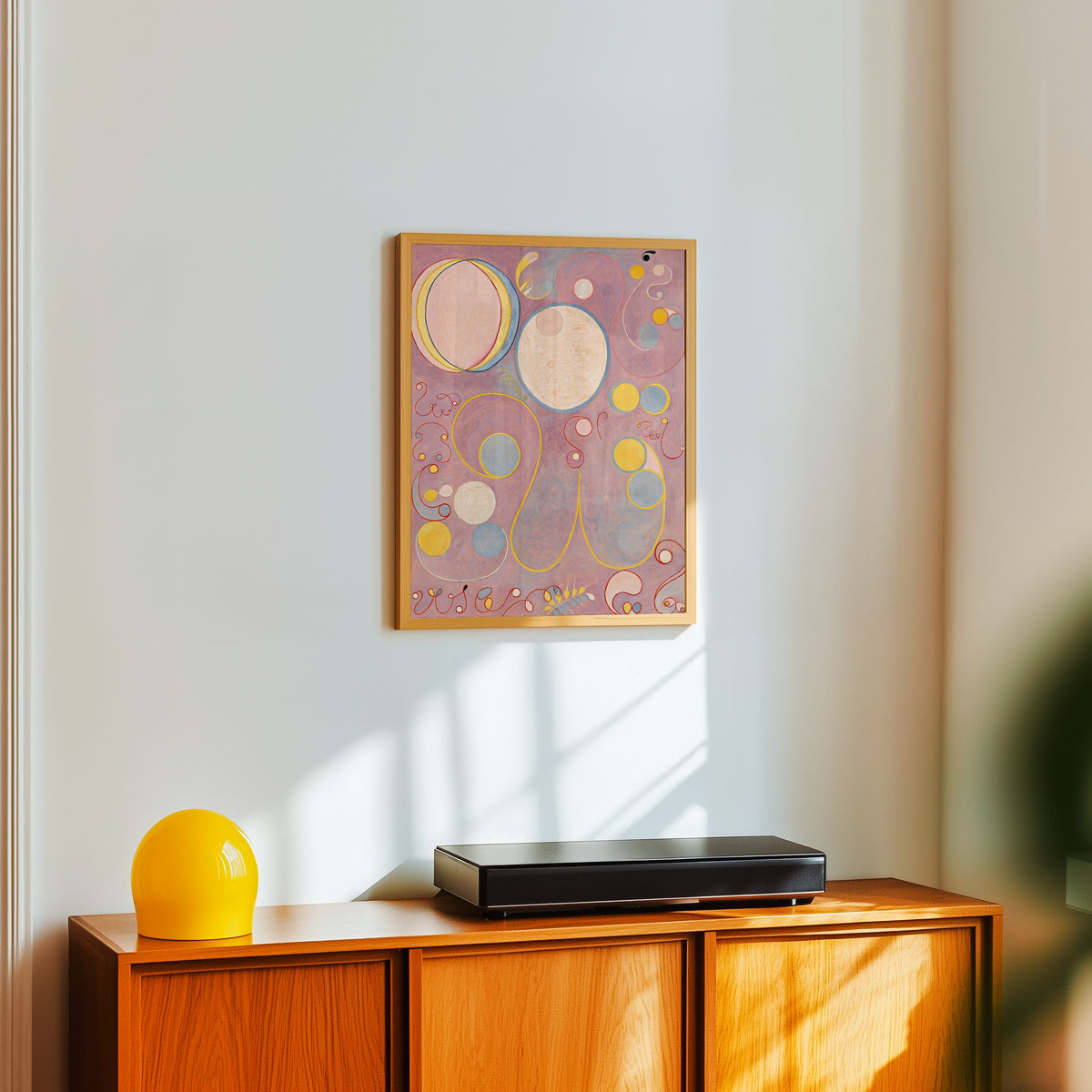 Framed art print of The Ten Largest, No. 8, Adulthood by Hilma af Klint, in a light wood frame on a white wall above an orange sideboard