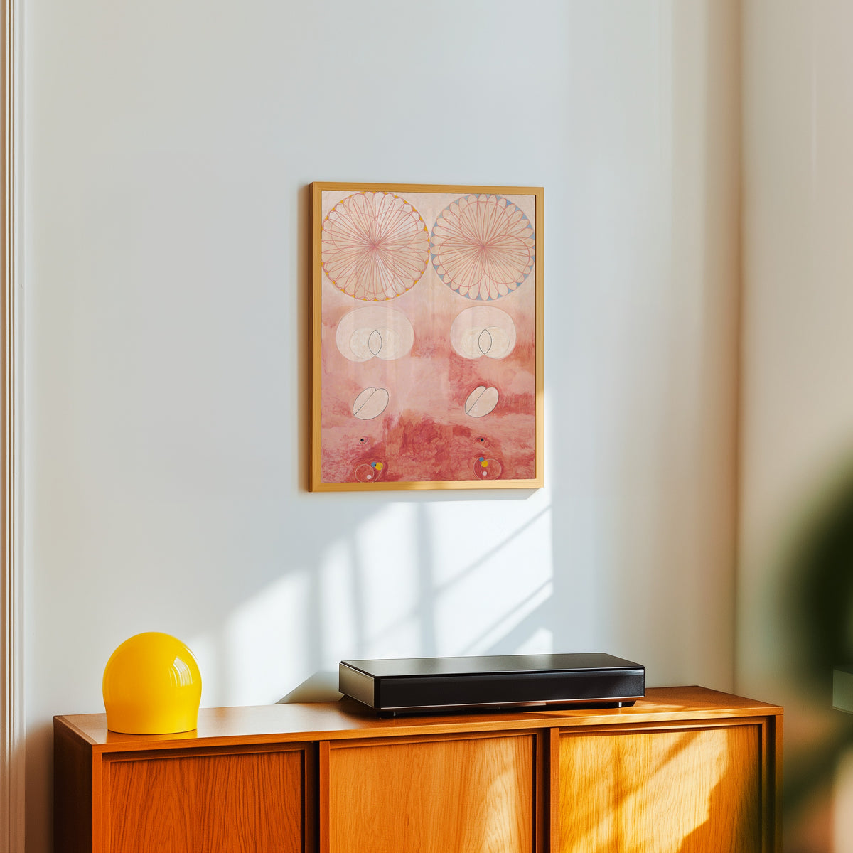 Framed art print of The Ten Largest, No. 9, Old Age by Hilma af Klint, in a light wood frame on a white wall above an orange sideboard