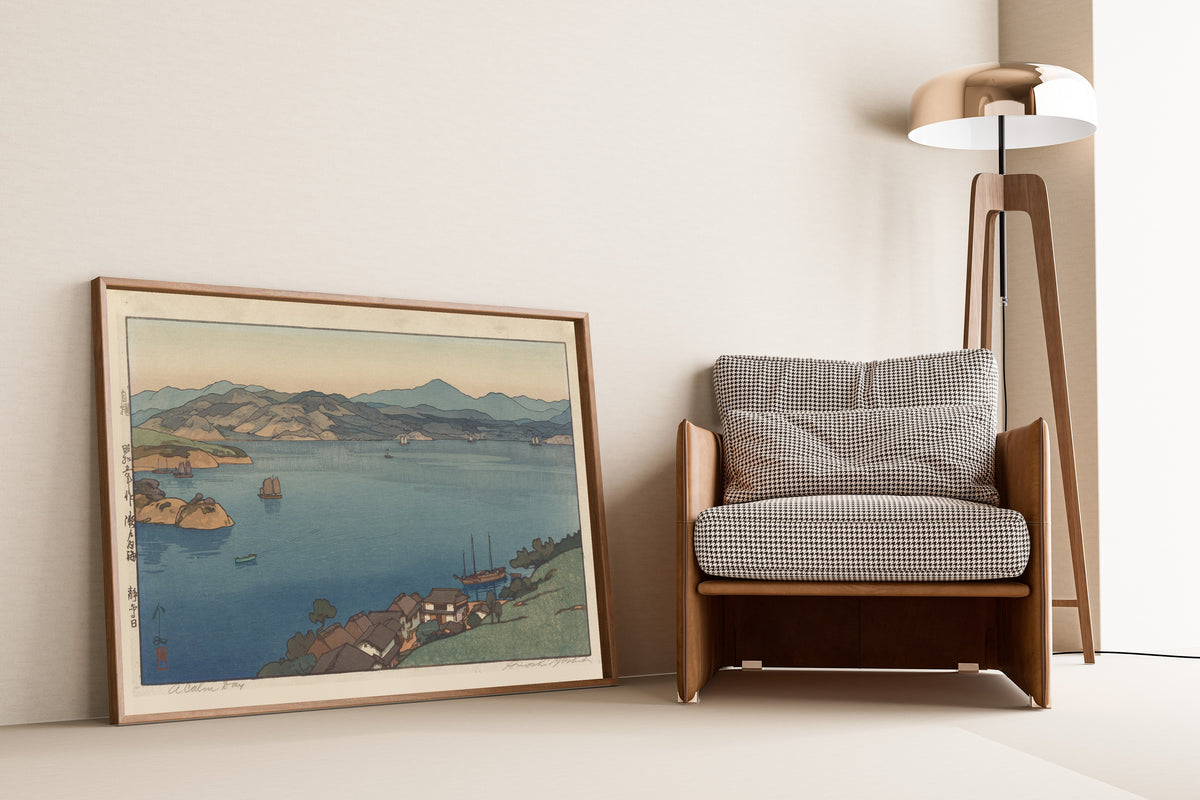 Framed art print of A Calm Day by Hiroshi Yoshida, leaning against a wall beside an armchair and a floor lamp