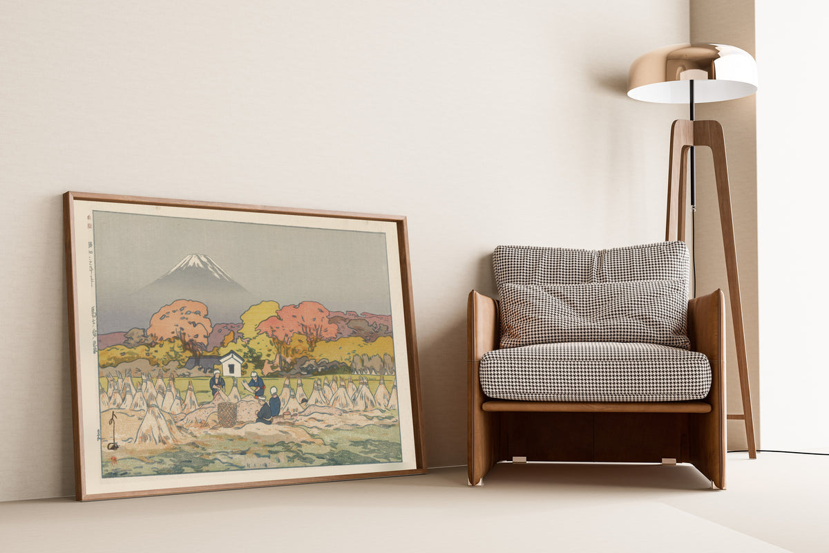 Framed art print of Autumn by Hiroshi Yoshida, leaning against a wall beside an armchair and a floor lamp