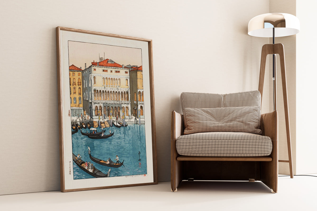 Framed art print of Canal in Venice by Hiroshi Yoshida, leaning against a wall beside an armchair and a floor lamp
