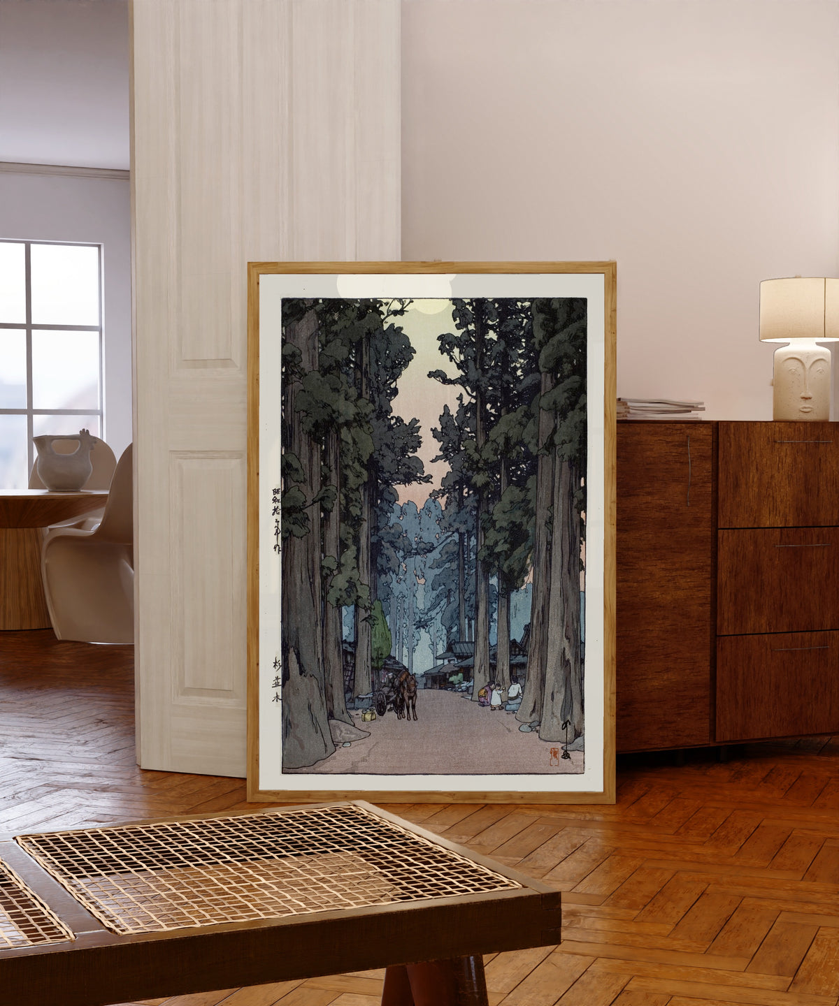 Framed art print of Cryptomeria Avenue by Hiroshi Yoshida, in a light wood frame leaning in a warm room with a parquet floor