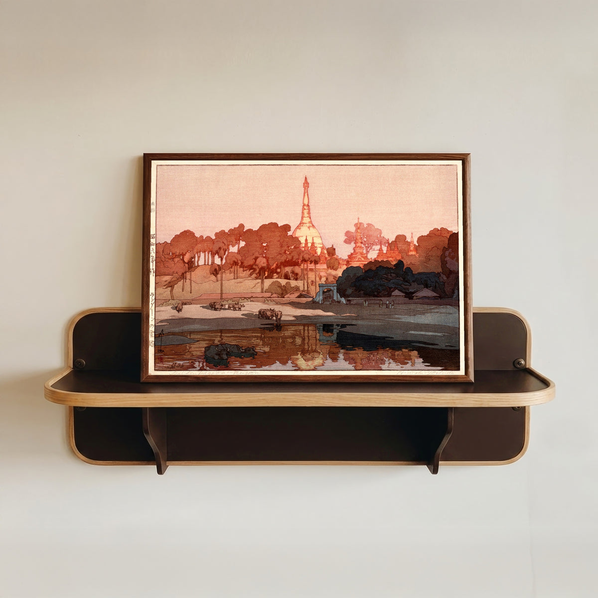 Framed art print of Golden Pagoda in Rangoon by Hiroshi Yoshida, in a dark wood frame resting on a wall shelf