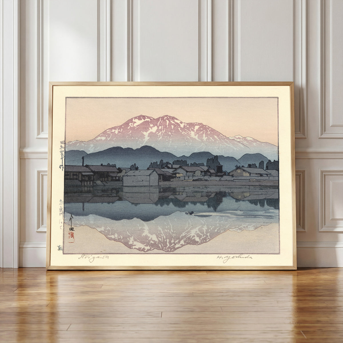 Framed art print of Itoigawa Morning by Hiroshi Yoshida, in a light wood frame leaning against a panelled white wall