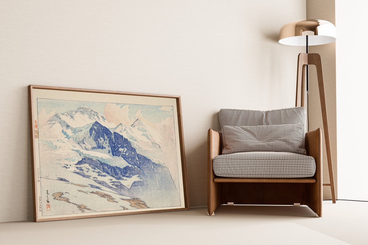 Framed art print of Jungfrau by Hiroshi Yoshida, leaning against a wall beside an armchair and a floor lamp