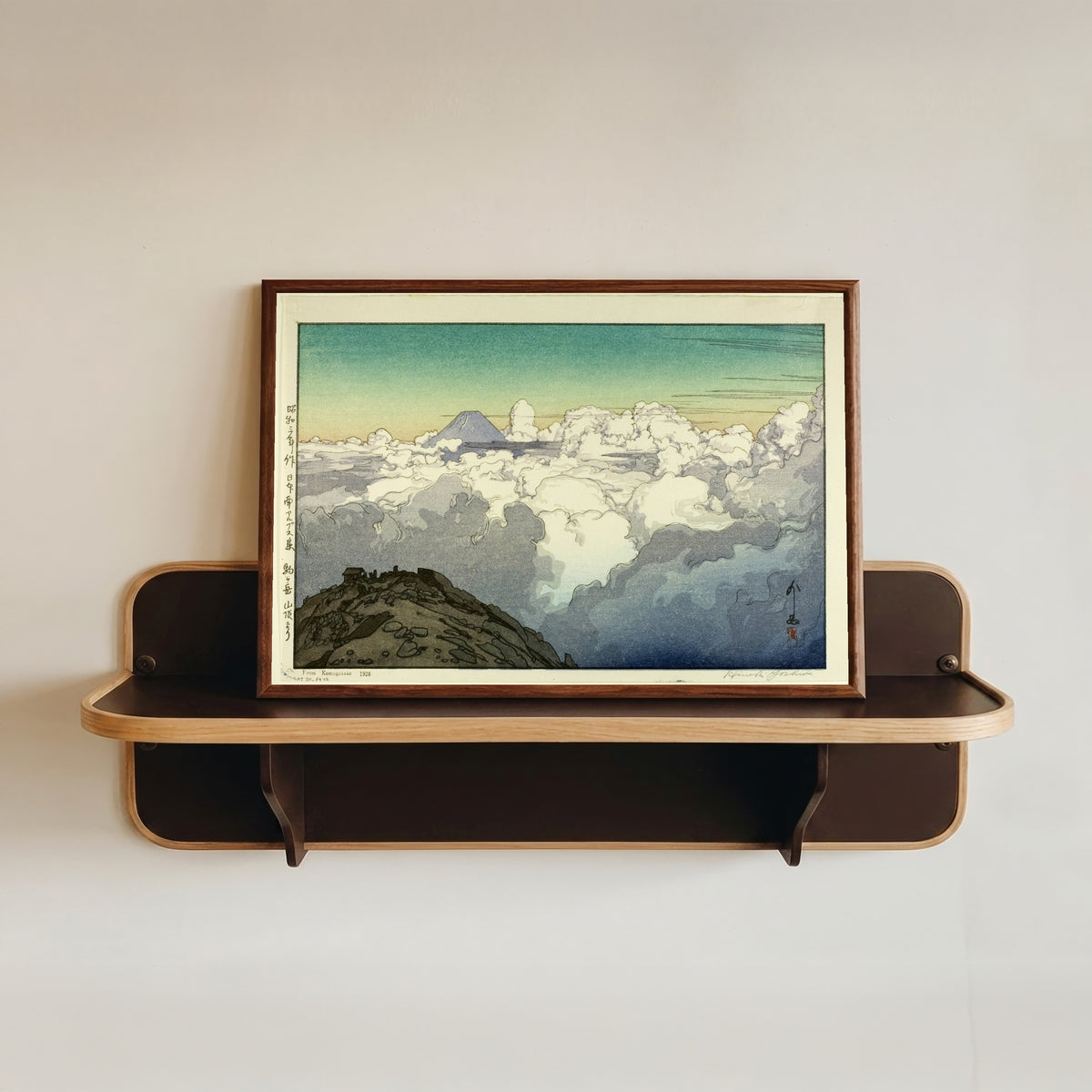 Framed art print of Komagatake Mountain by Hiroshi Yoshida, in a dark wood frame resting on a wall shelf