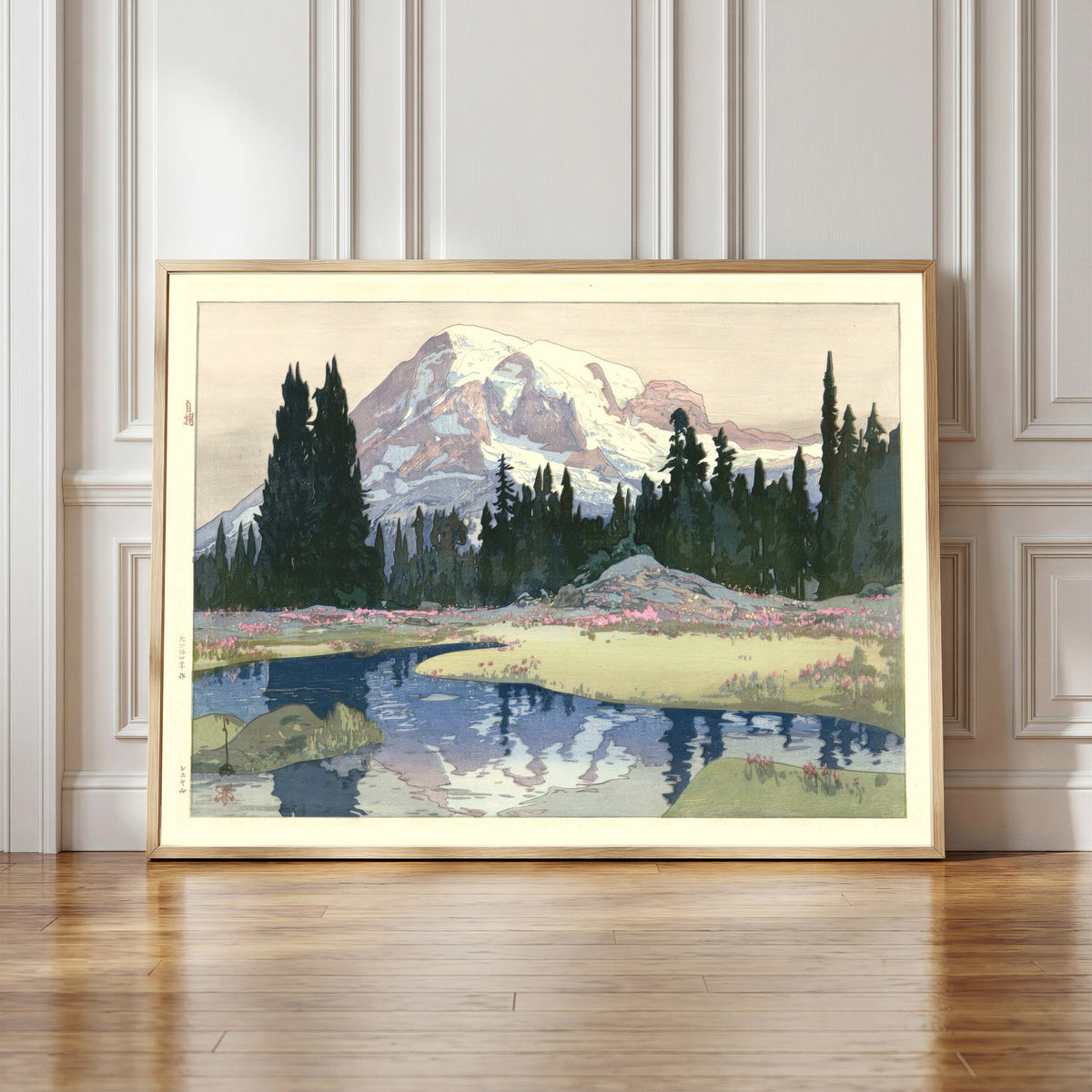 Framed art print of Mount Rainier, Washington State by Hiroshi Yoshida, in a light wood frame leaning against a panelled white wall