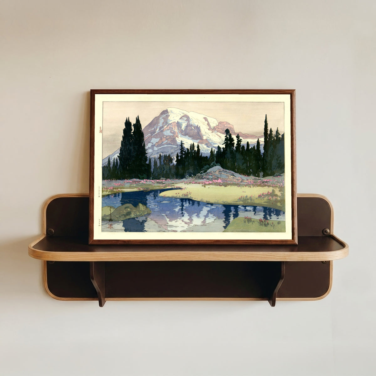 Framed art print of Mount Rainier, Washington State by Hiroshi Yoshida, in a dark wood frame resting on a wall shelf
