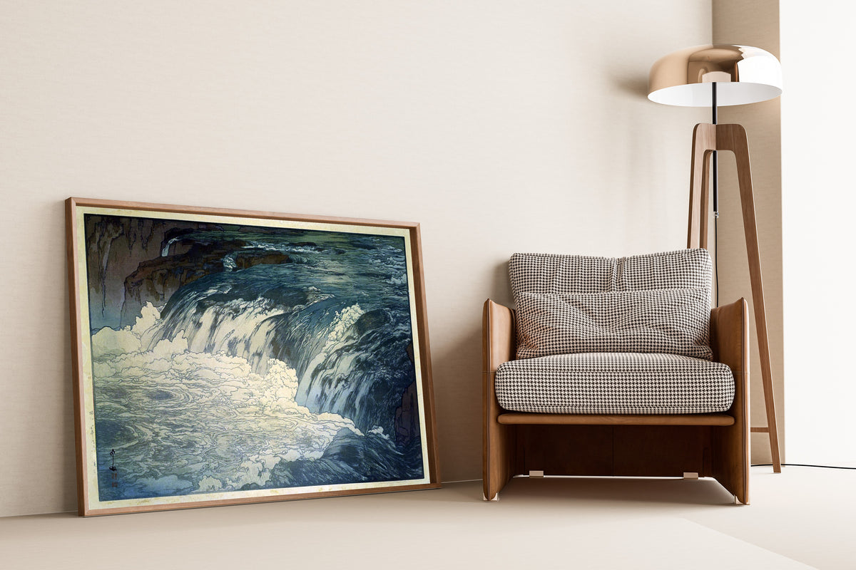 Framed art print of Rapids by Hiroshi Yoshida, leaning against a wall beside an armchair and a floor lamp