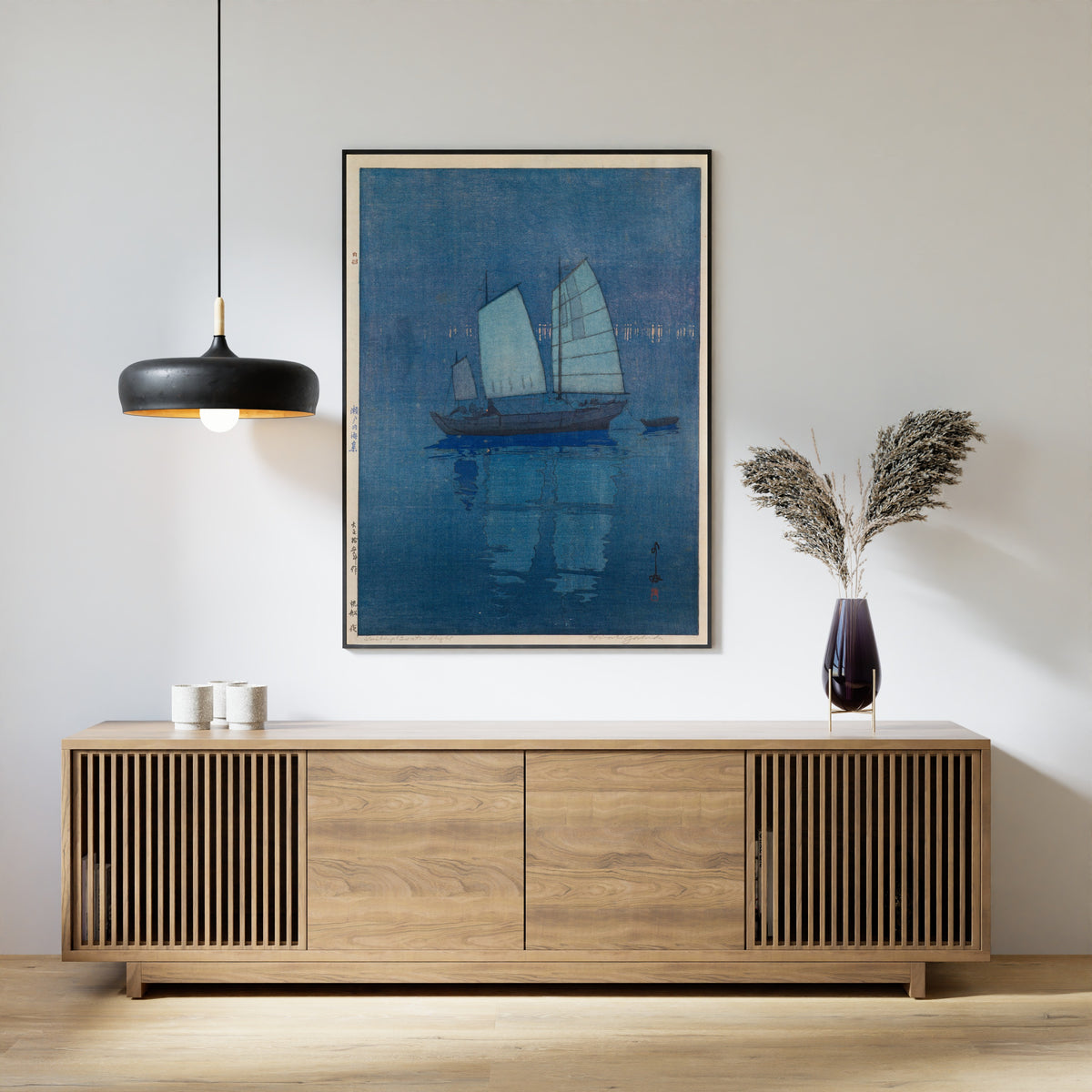 Framed art print of Sailing Boats, Night by Hiroshi Yoshida, above a slatted wood sideboard