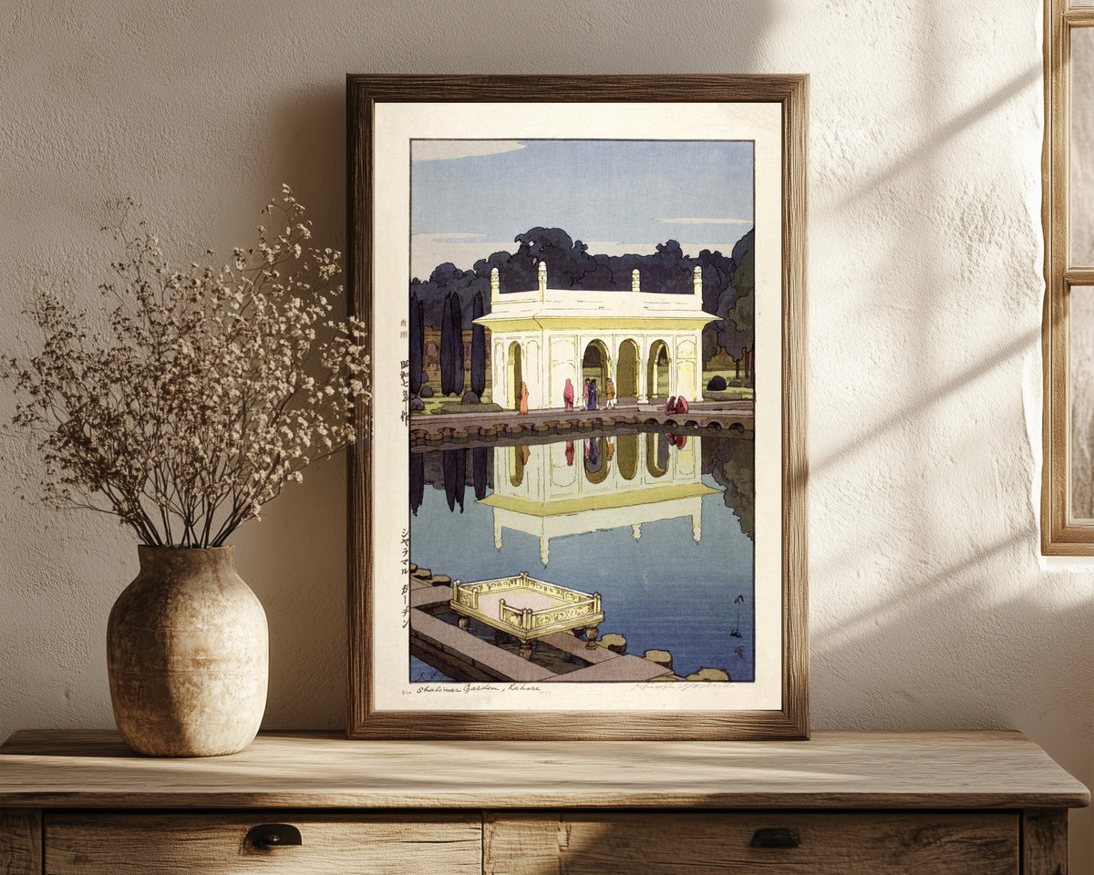 Framed art print of Shalimar Gardens, Lahore by Hiroshi Yoshida, in a dark wood frame leaning on a rustic console beside dried flowers