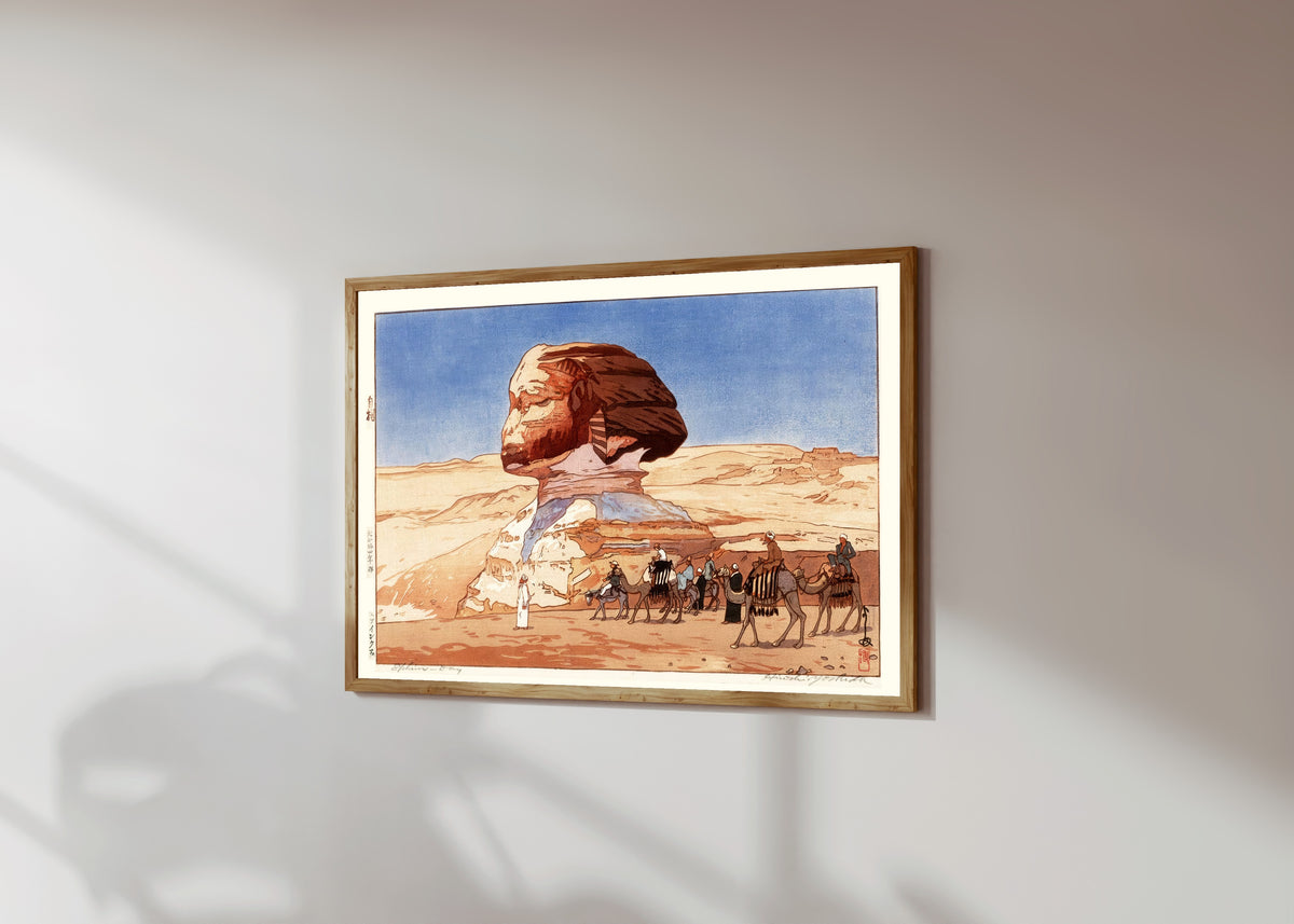 Framed art print of Sphinx at Day by Hiroshi Yoshida, in a light wood frame on a sunlit white wall, seen at a slight angle
