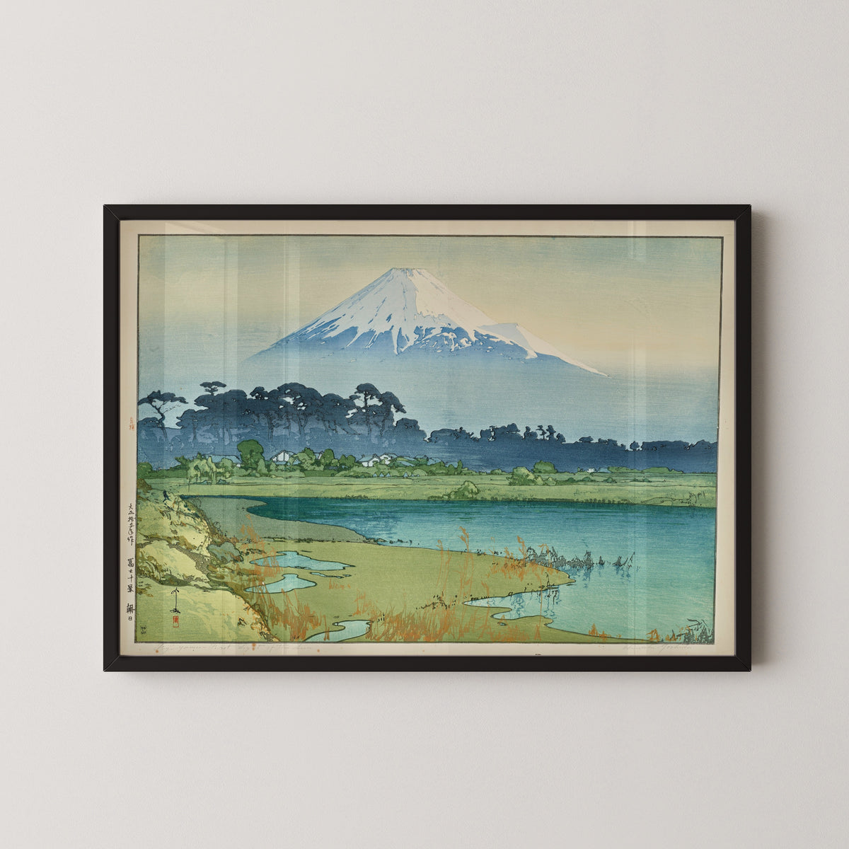 Framed art print of Sunrise by Hiroshi Yoshida, in a black frame on a pale wall