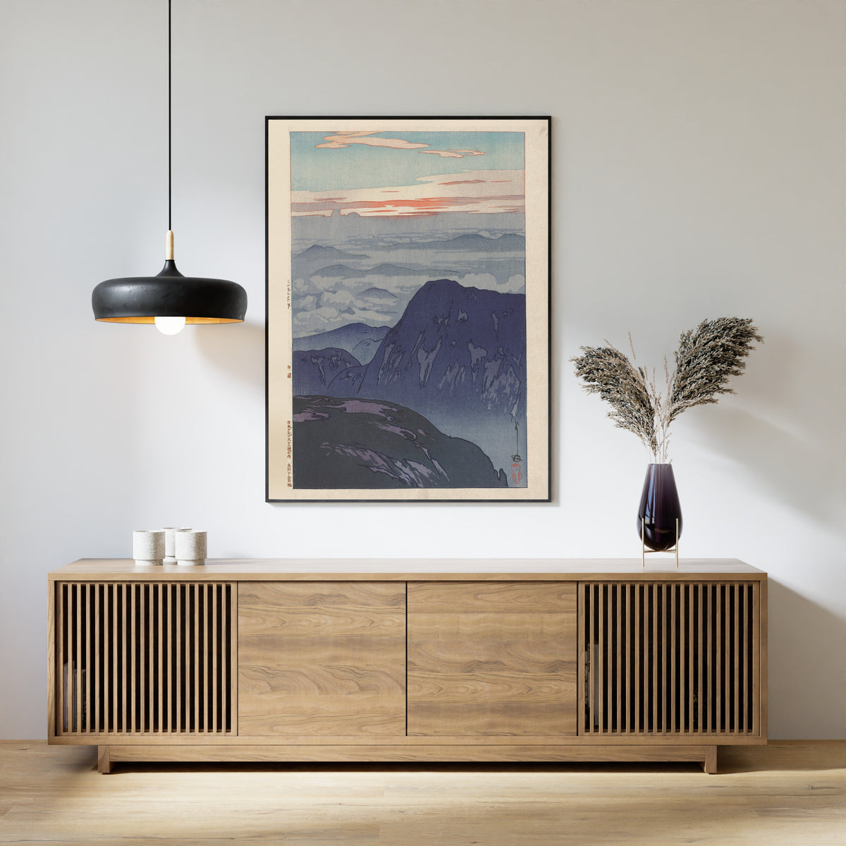 Framed art print of Sunrise on Eboshidake by Hiroshi Yoshida, above a slatted wood sideboard