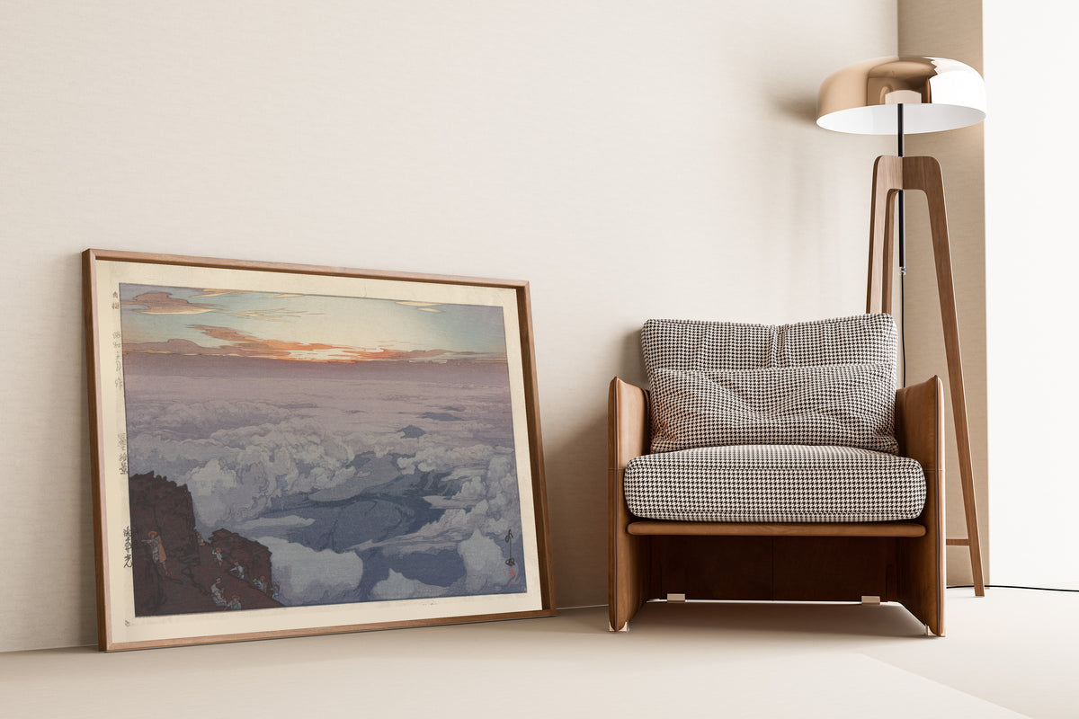 Framed art print of Sunrise Rite by Hiroshi Yoshida, leaning against a wall beside an armchair and a floor lamp