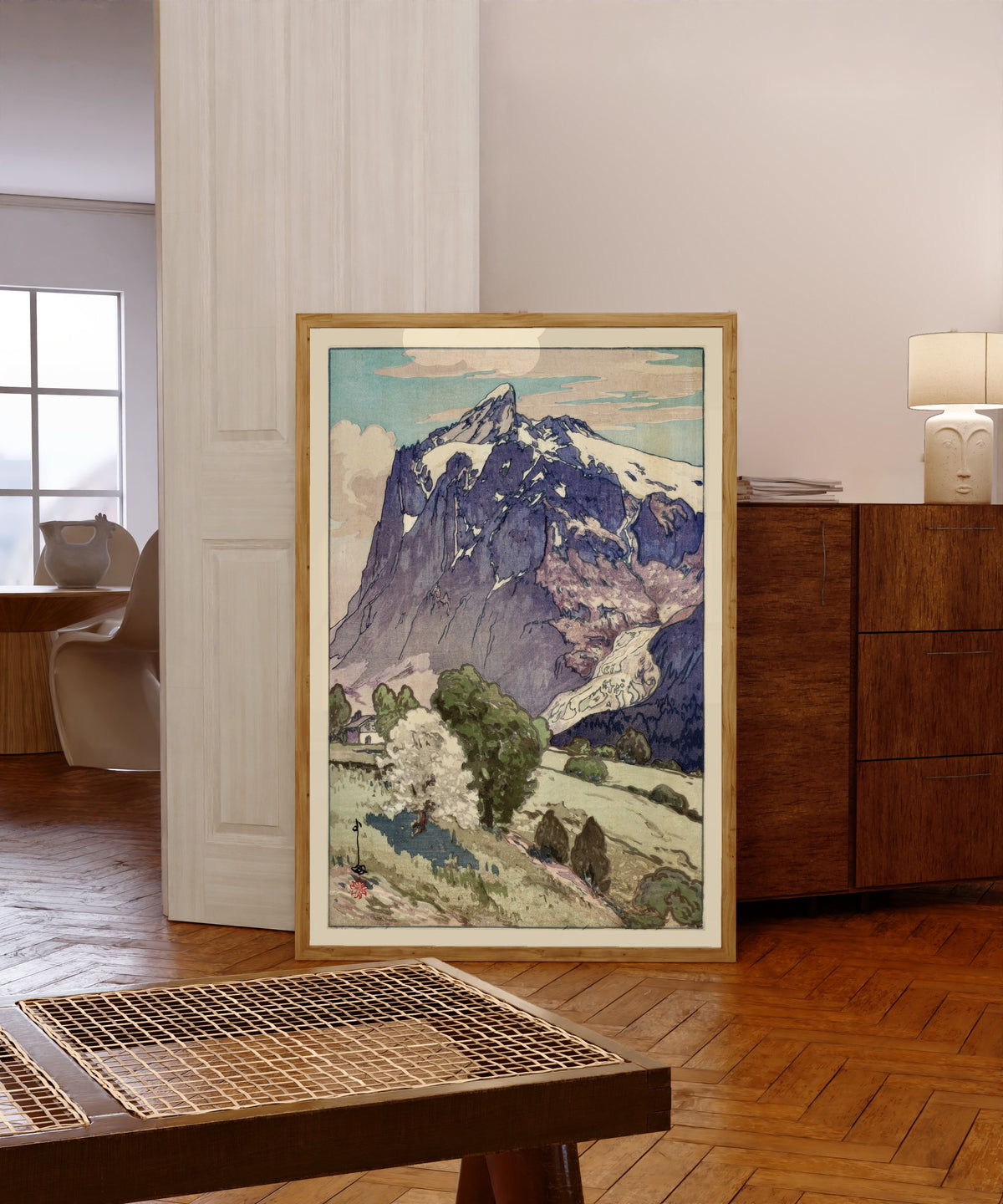 Framed art print of The Wetterhorn, Switzerland by Hiroshi Yoshida, in a light wood frame leaning in a warm room with a parquet floor