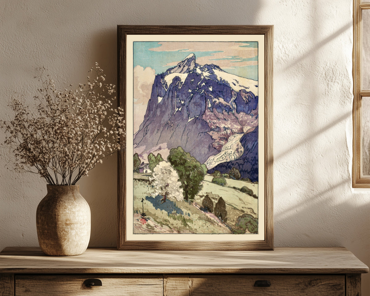 Framed art print of The Wetterhorn, Switzerland by Hiroshi Yoshida, in a dark wood frame leaning on a rustic console beside dried flowers