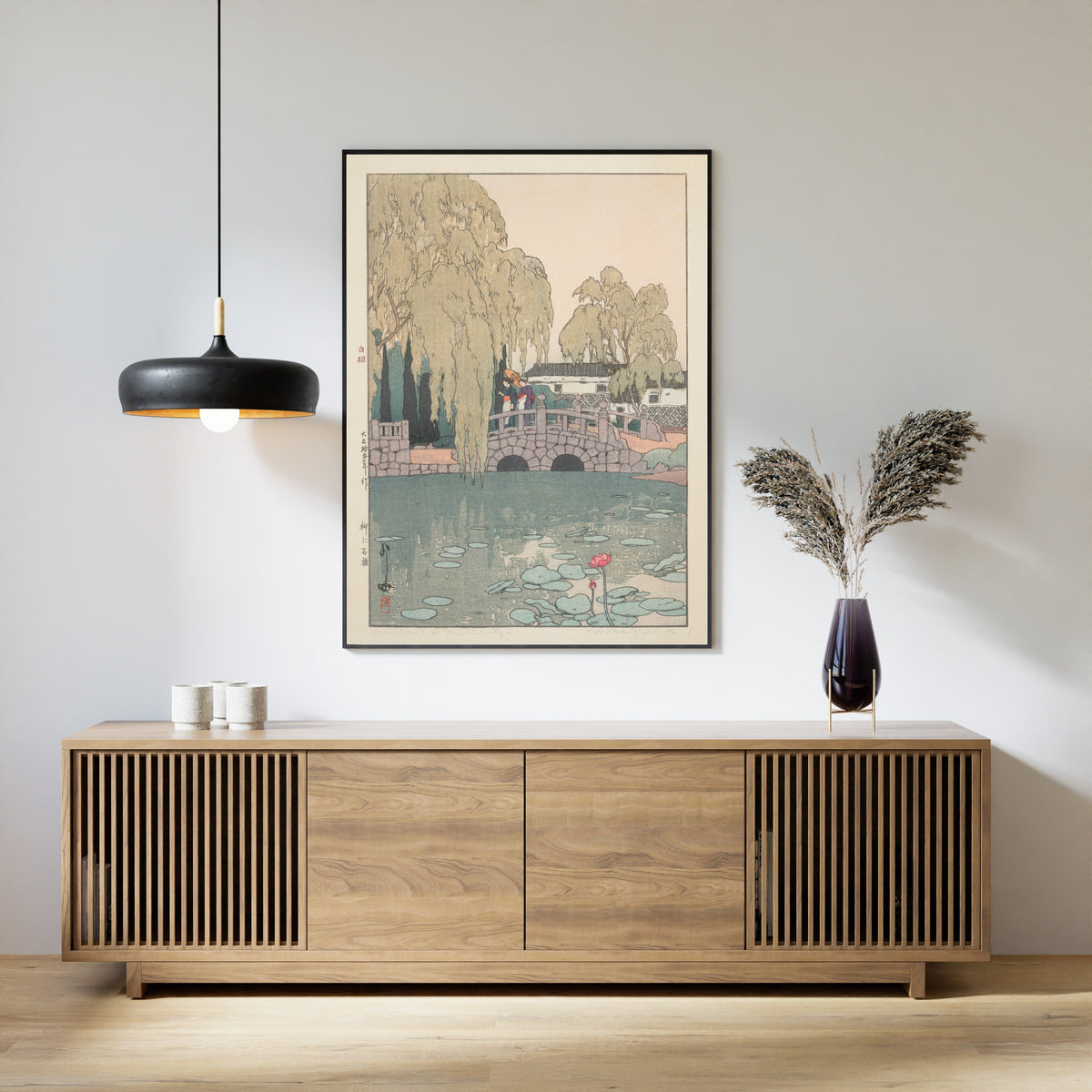 Framed art print of Willow and Stone Bridge by Hiroshi Yoshida, above a slatted wood sideboard