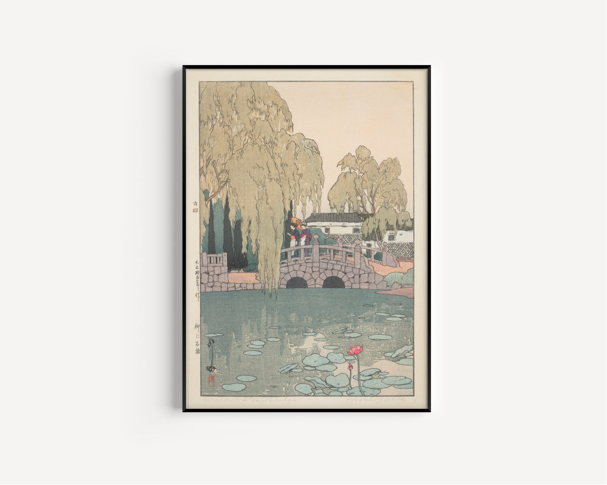 Framed art print of Willow and Stone Bridge by Hiroshi Yoshida, in a slim black frame on a plain white wall