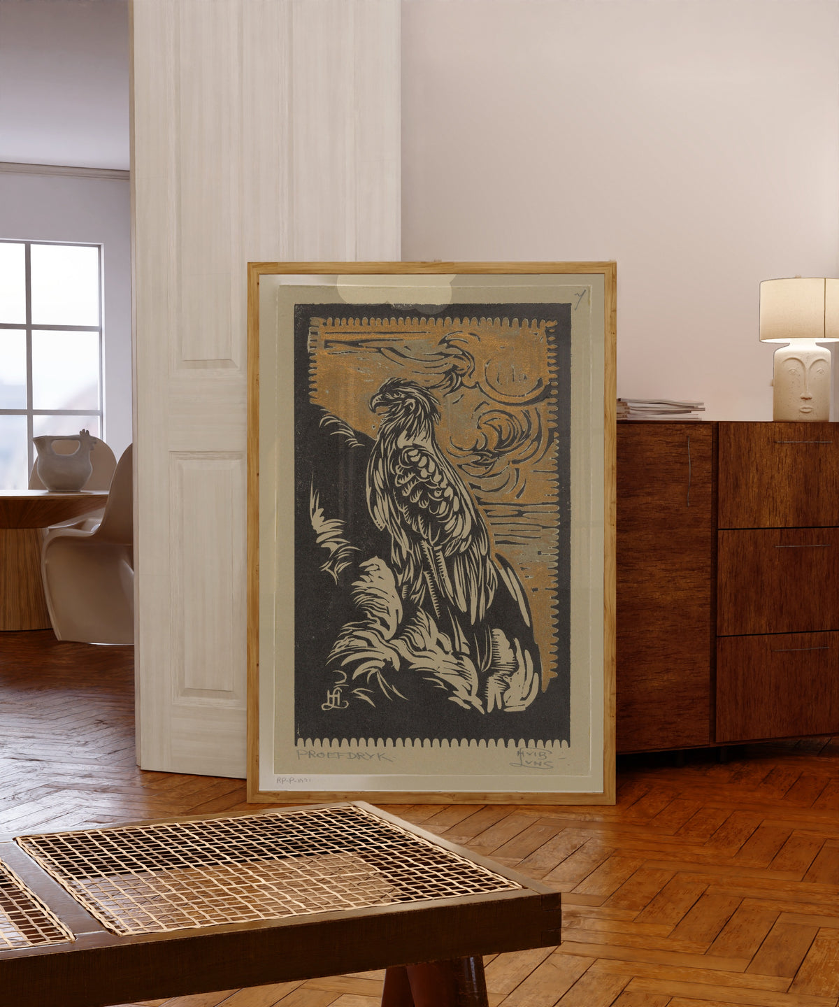 Framed art print of Arend [Eagle] by Huib Luns, in a light wood frame leaning in a warm room with a parquet floor